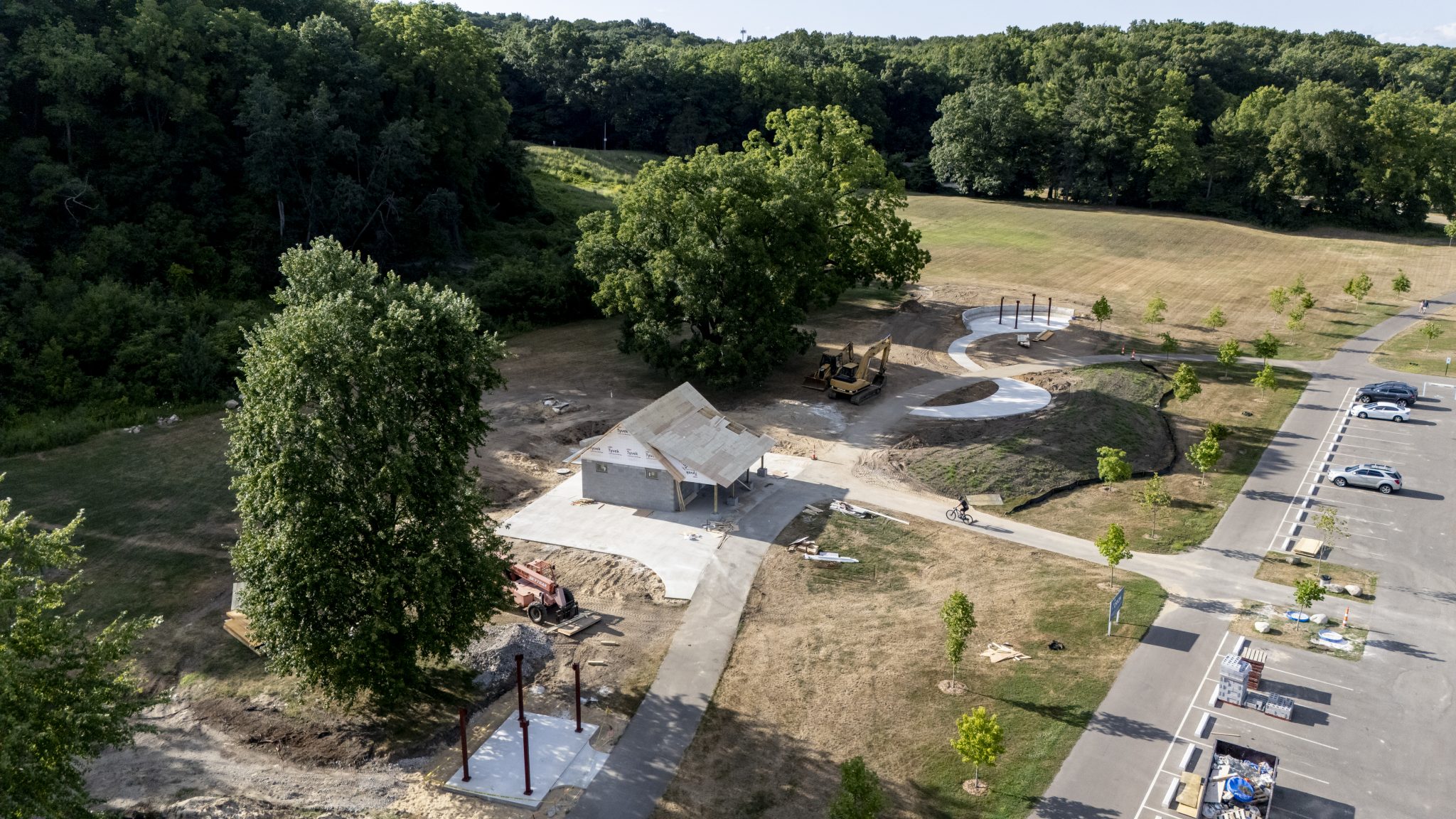 Aerial view of park and pavilion construction in a mowed field surrounded by trees