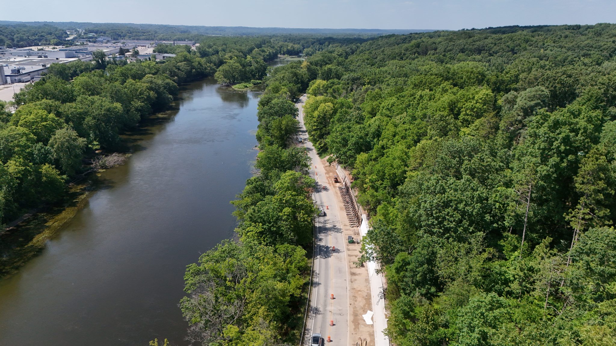 Aerial view of new pedestrian trail separated from the road by a retaining wall and surrounded by trees.