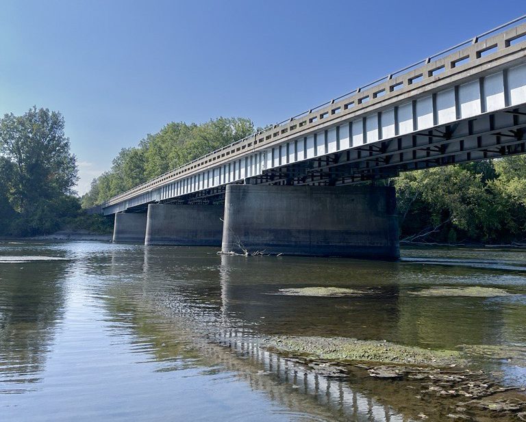 Bridge above a river with lower water and blue sky background